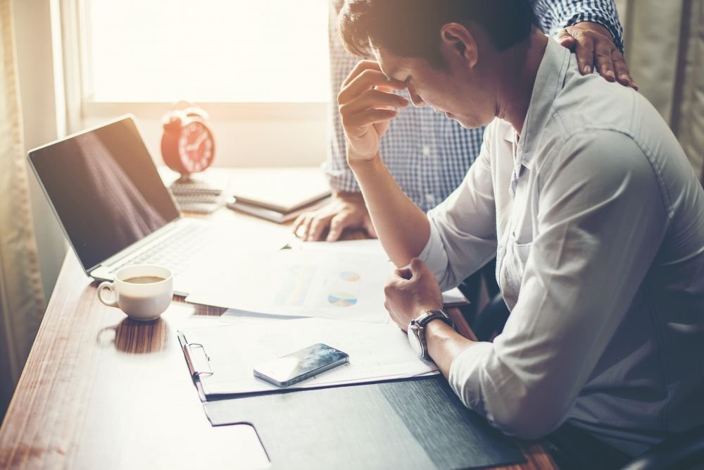 Čovjek koji je umoran i razmišlja za radnim stolom pod utjecajem negativnih dropshipping iskustva