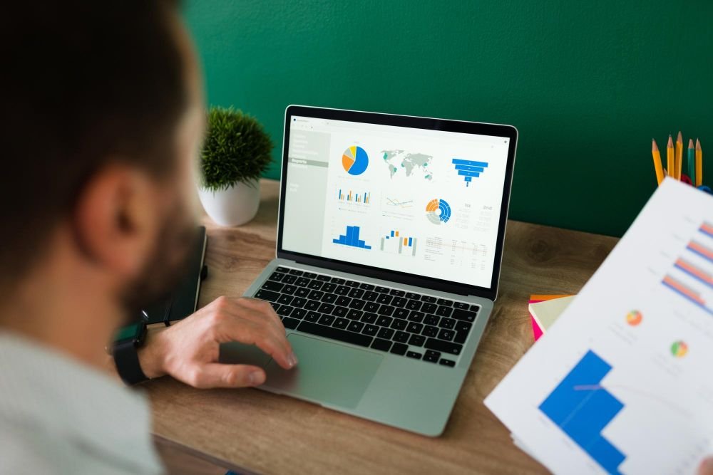muškarac radi na laptopu sa statistikom na ekranu