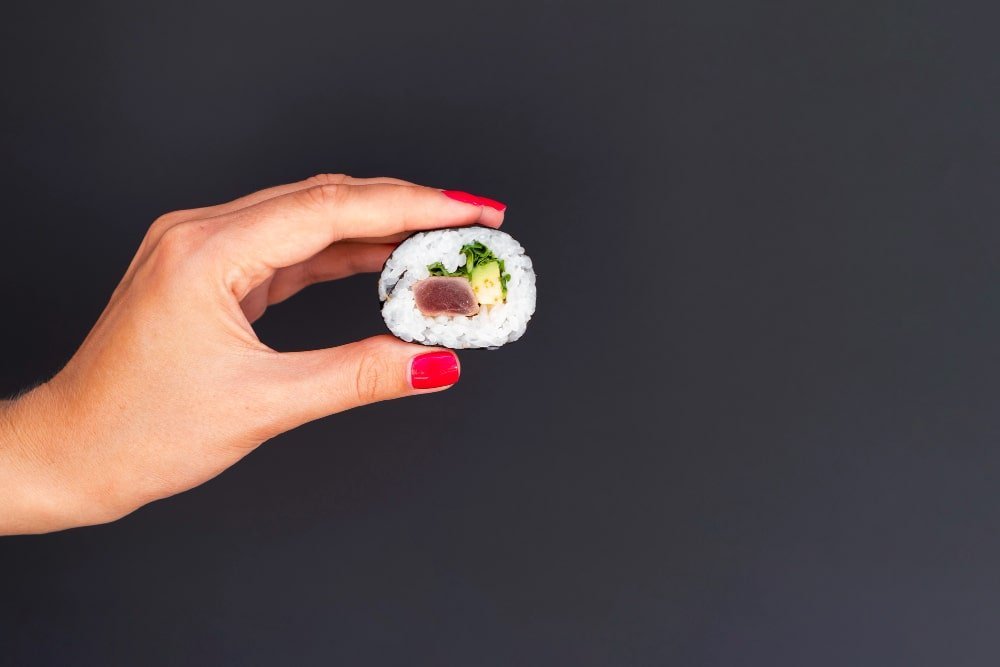 Zenska ruka drzi sushi i prikazuje usku nisu u dropshippingu